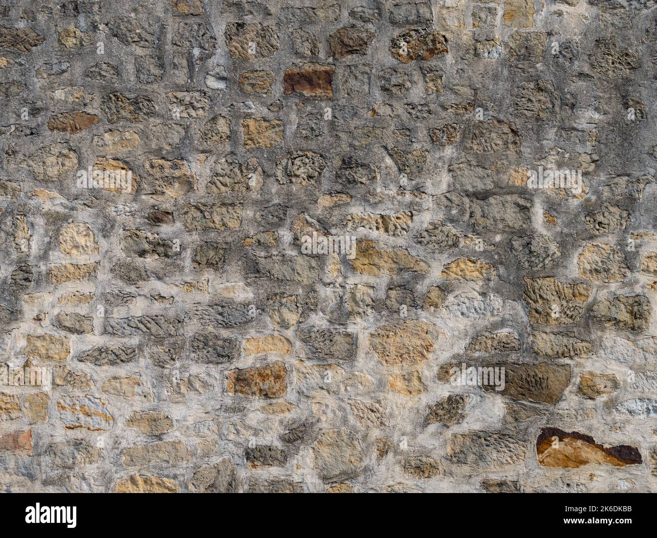 Old stone wall texture with different natural stones. Abstract background from a building exterior. Weathered rough masonry pattern of the material. Stock Photo
