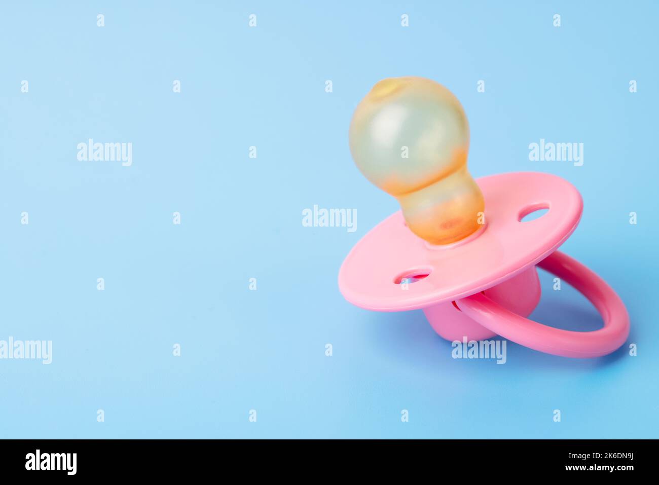 Orthodontic pacifier on a blue background. Pink baby pacifier Stock