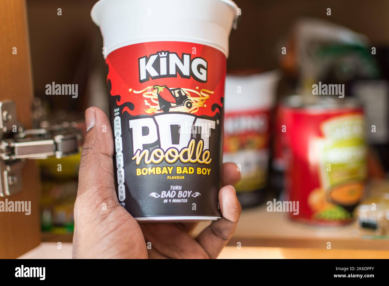 Adult male picking an Pot noodles from home food cupboard Stock Photo Alamy