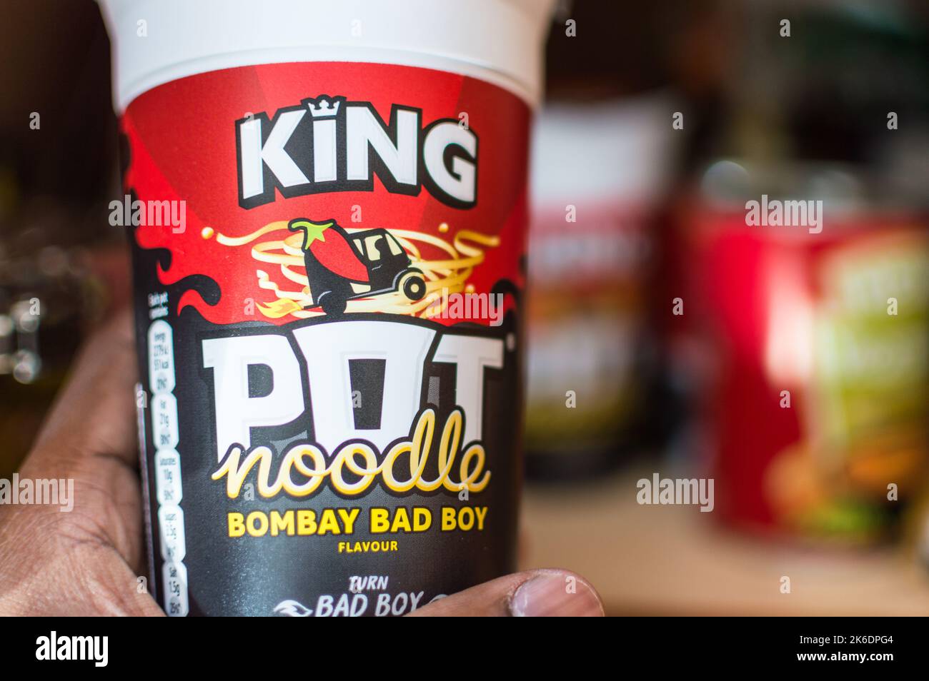 Adult male picking an Pot noodle from home food cupboard Stock Photo