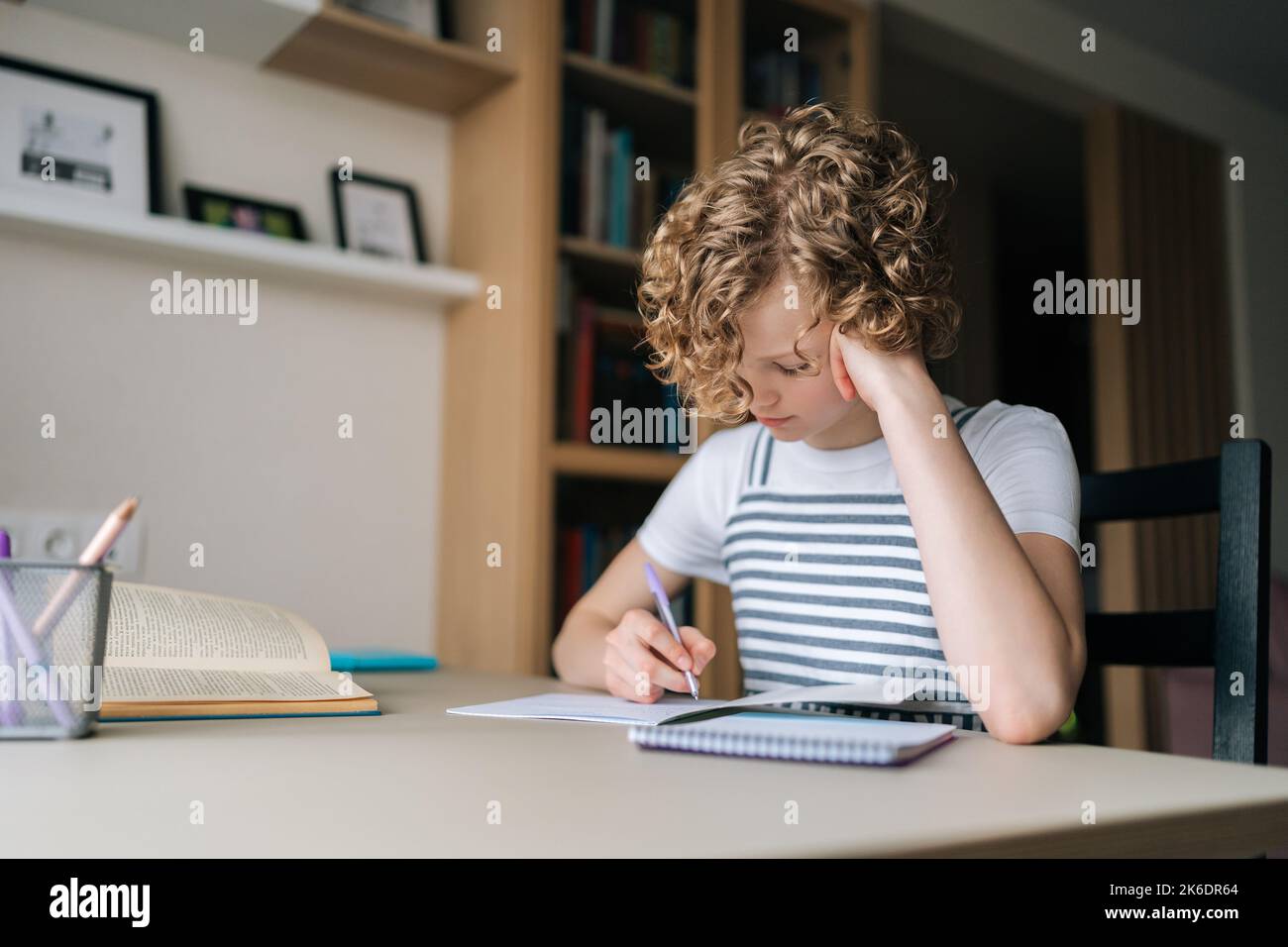 Doing Boo Portrait of pensive little child schoolgirl writing in exercise book ...