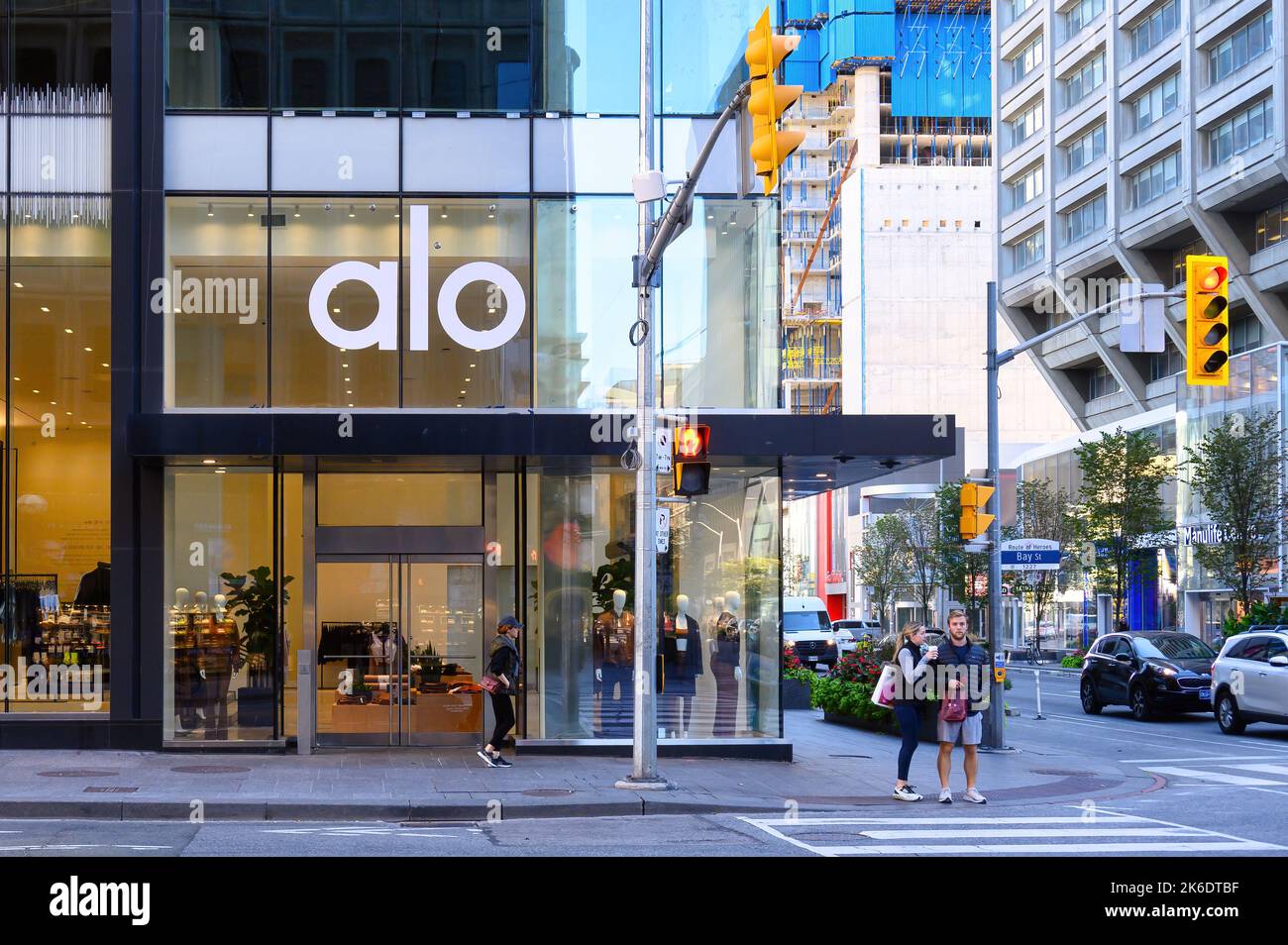 Alo retail store in Bloor Street. A couple waits to cross the street in the downtown district. Stock Photo