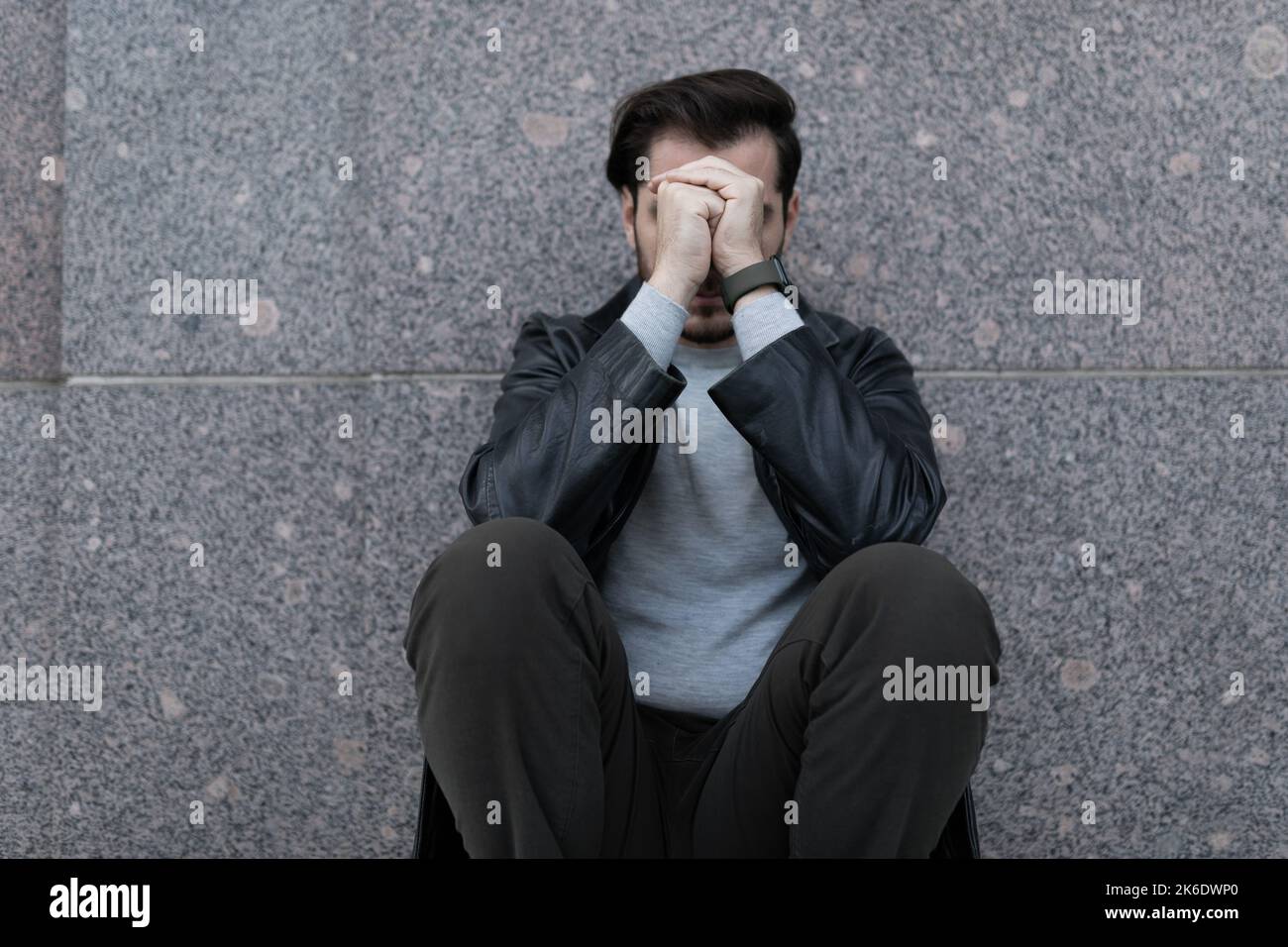 grieving man sitting upset covering his face with his hands Stock Photo