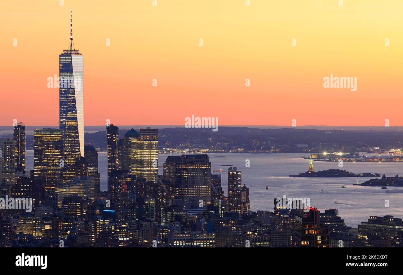 Aerial view of Lower Manhattan skyline illuminated at sunset with orange background in New York City, USA Stock Photo