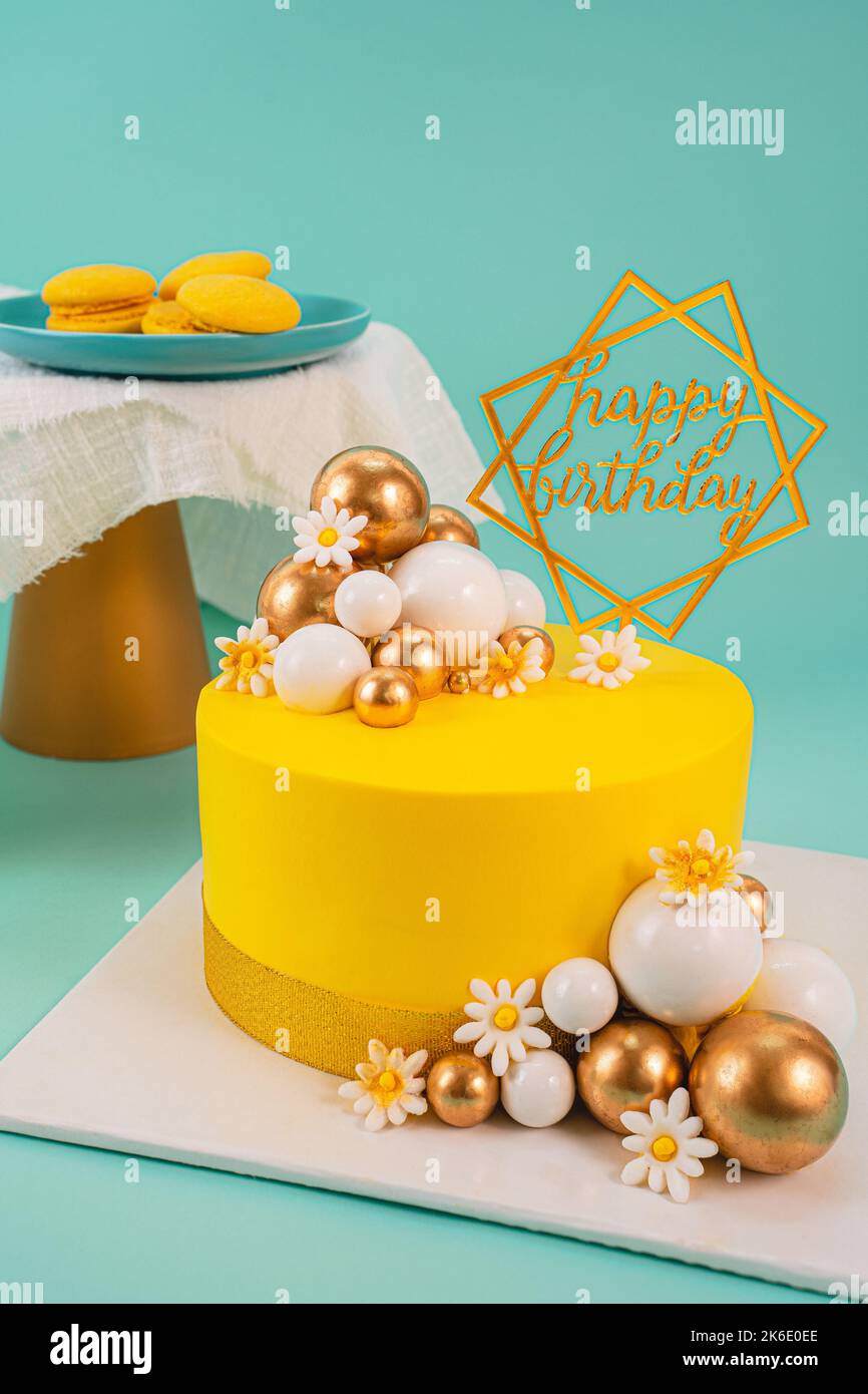 A yellow birthday cake decorated with balls in different colors and ...