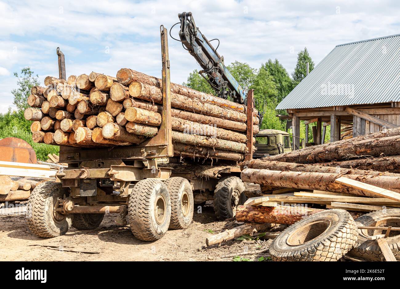 Timber carrier with large sawn logs at the wood storage place. Forest