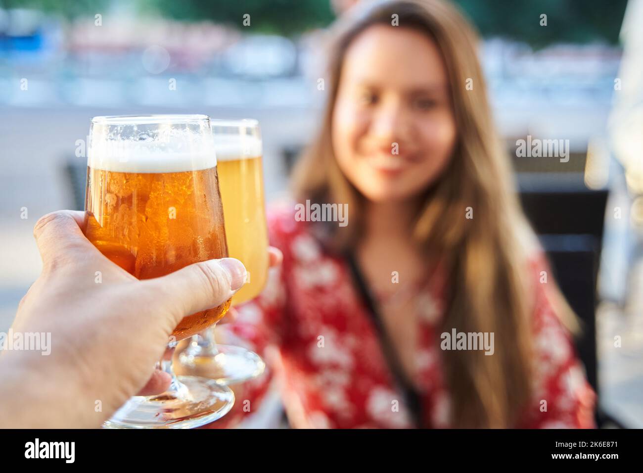 selective focus. Closeup of two hands clinking beer stein glasses. Toasting with a pint of draft beers. Detail of happy couple hands raising toast wit Stock Photo