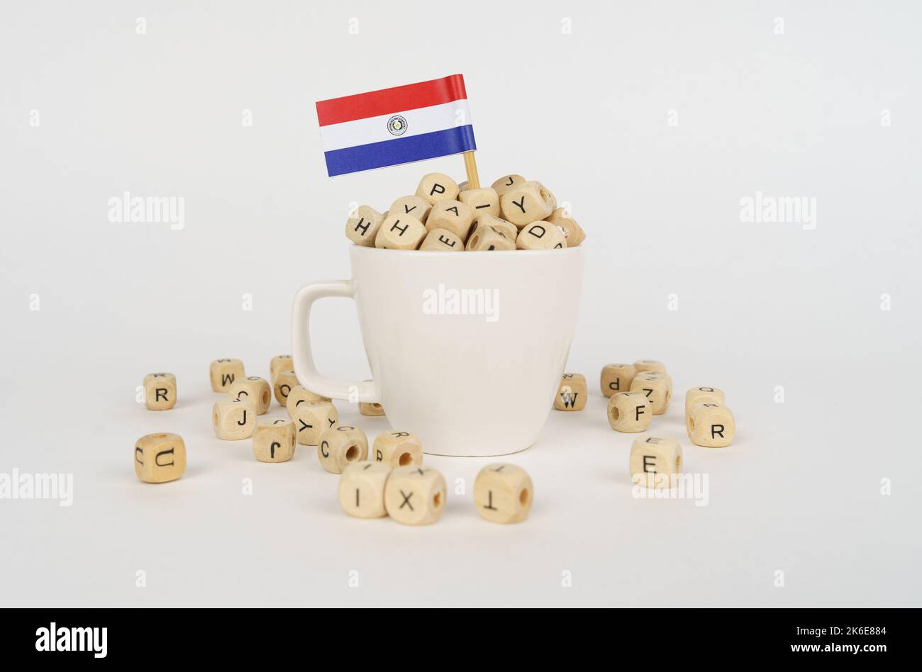The flag of Paraguay sticks out of a cup with dice on which letters are depicted. Symbol of education. Stock Photo