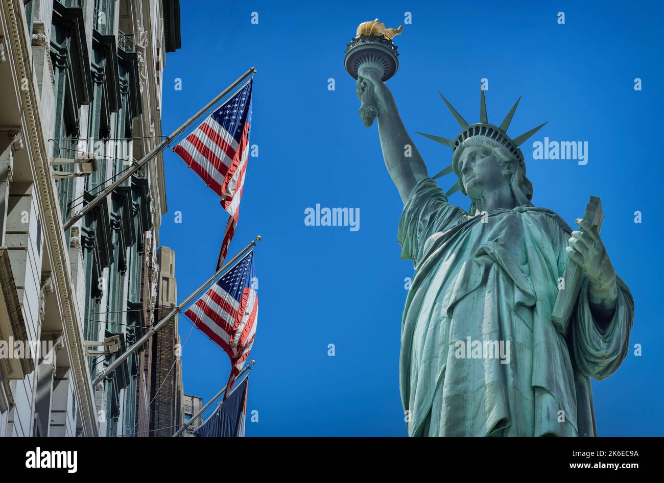 View Statue of Liberty near US building in flying flag United States America Stock Photo