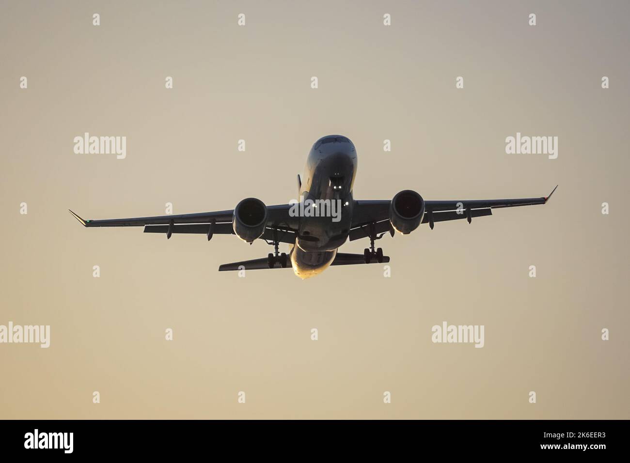 Silhouette of airliner landing at airport at sunset Stock Photo