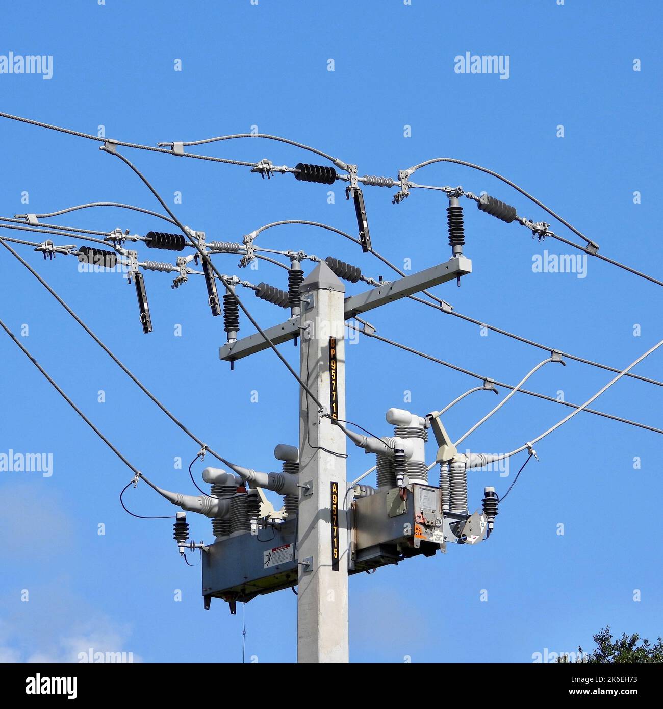 A low angle shot of a power transformer and electrical wires on a metal pole Stock Photo