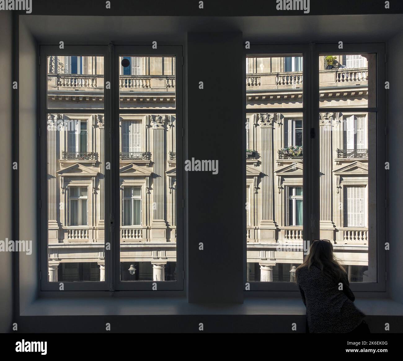 A woman looks out of a window in central Paris, France Stock Photo