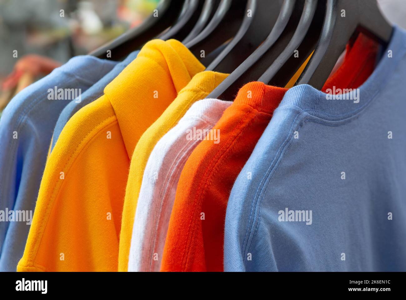 Variety of colorful t-shirts on black hangers at an outdoor shopping event Stock Photo