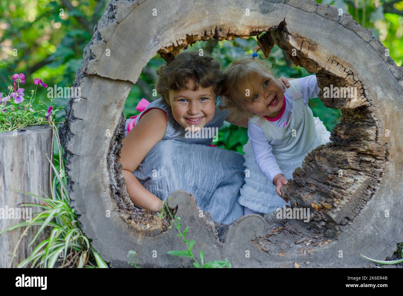 Two funny little girls having fun with a sleigh in beautiful park. Stock Photo