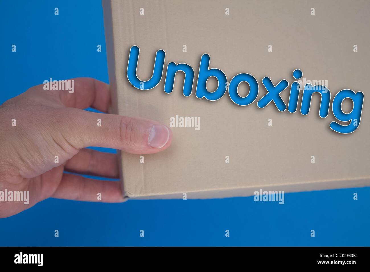 Unboxing word with cardboard box. Brown folded card box. Stock Photo