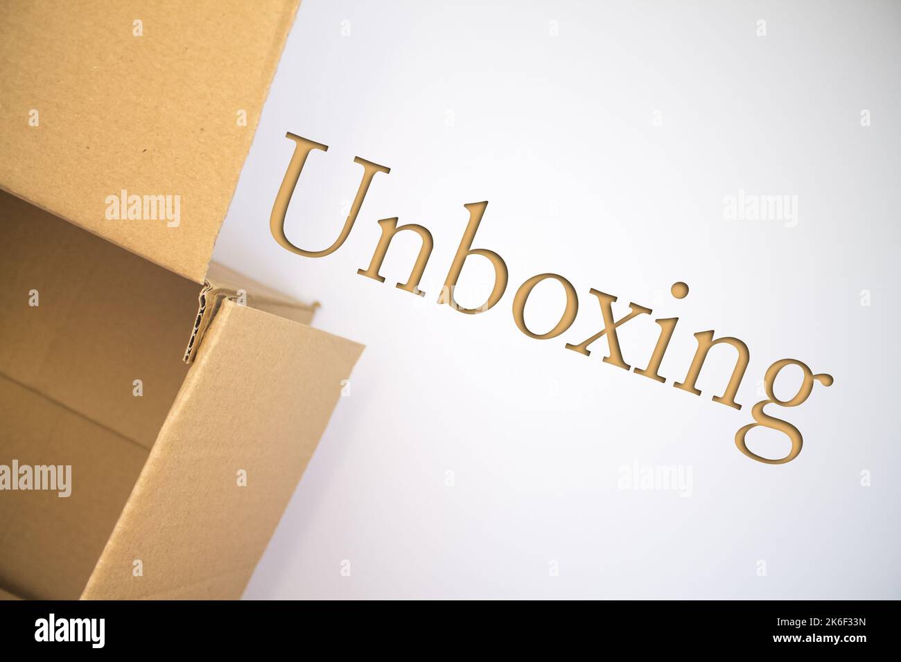 Unboxing word with cardboard box. Brown folded card box. Stock Photo