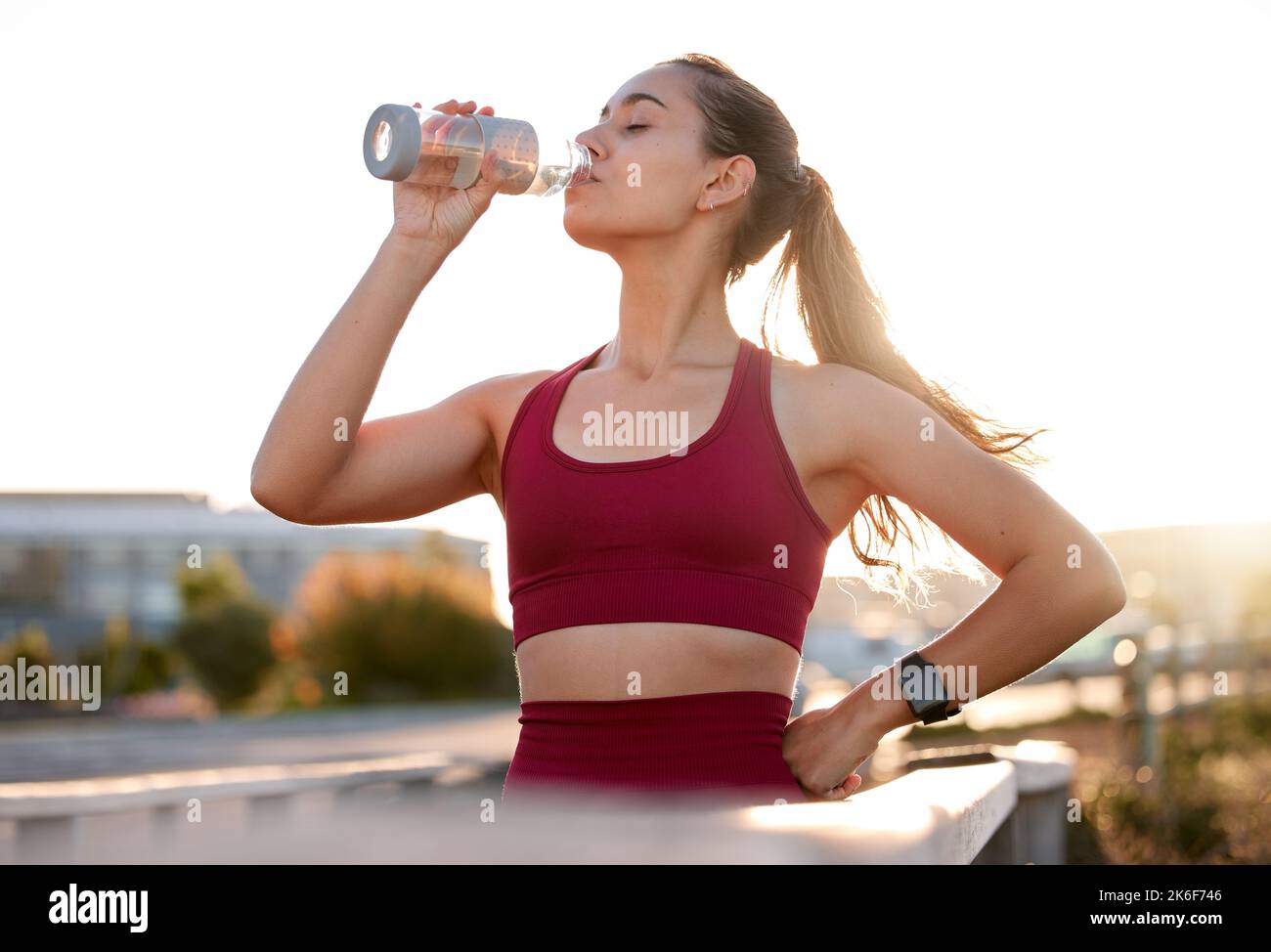 Keep hydrated at all times. a young woman drinking water while exercising in the city. Stock Photo