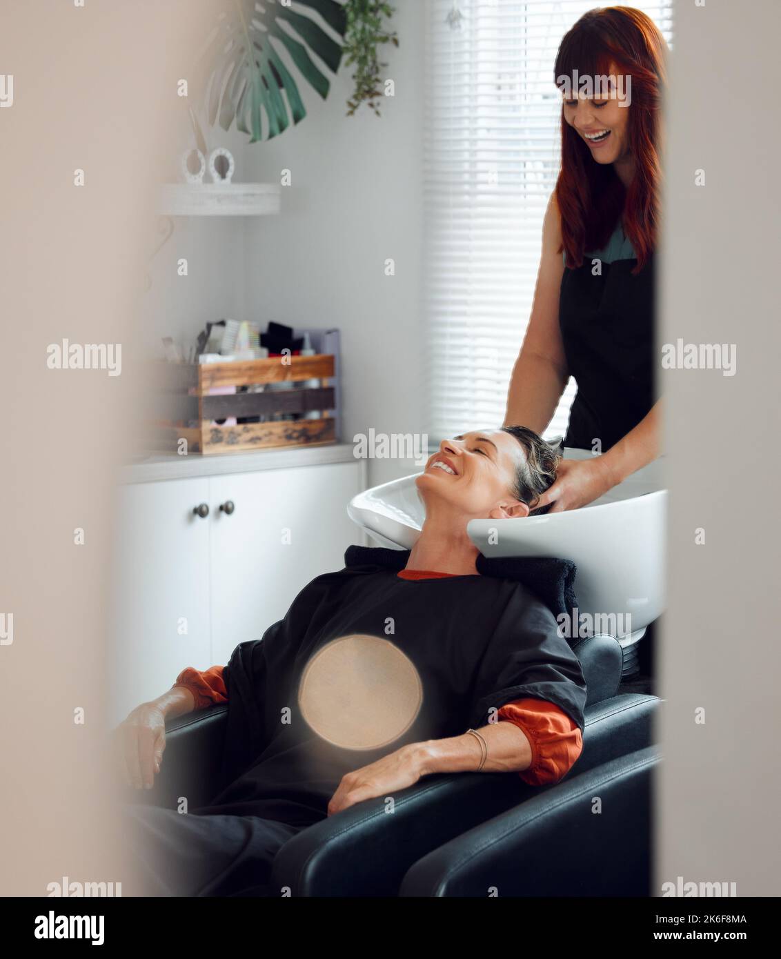 Hairdresser, woman client and hair care to relax and smile after washing in the basin. Salon, beauty spa and professional stylist with a female Stock Photo