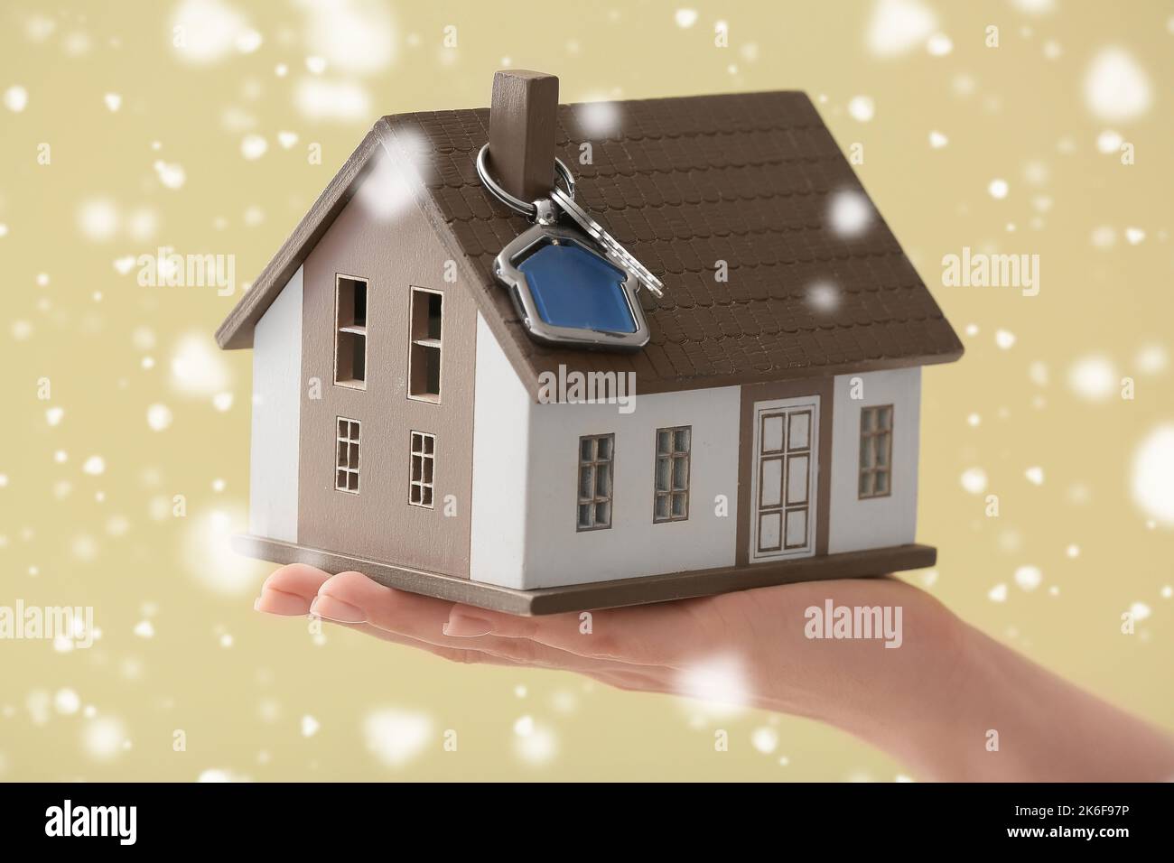 Female hand with model of house and key on yellow background with ...