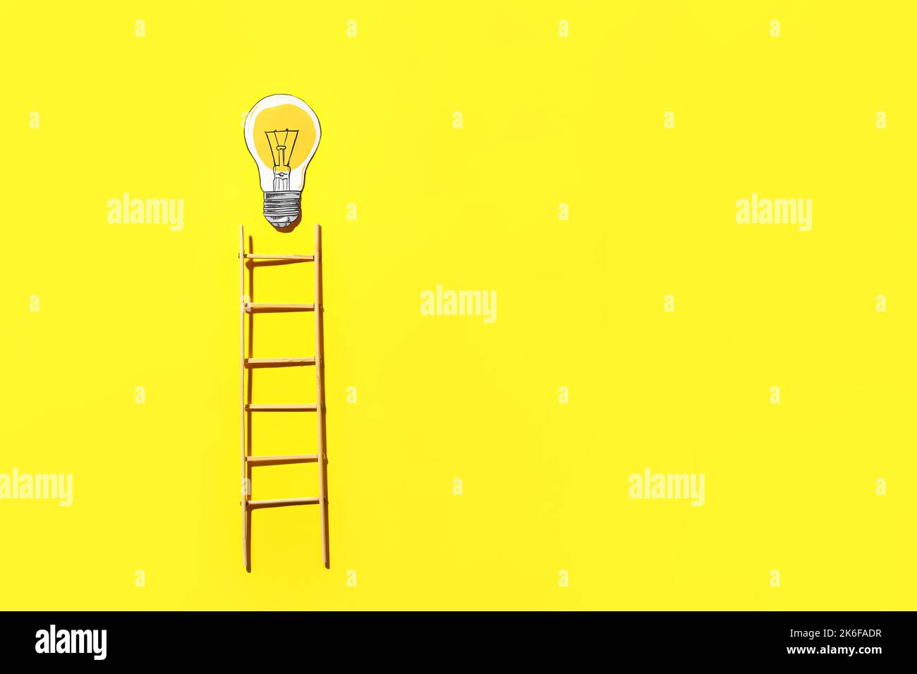 Ladder and light bulb on yellow background Stock Photo