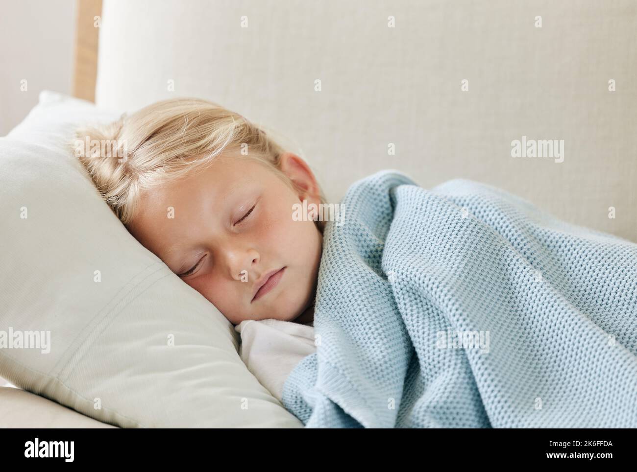 Mmm, beaches. an unwell little girl resting on the sofa at home. Stock Photo