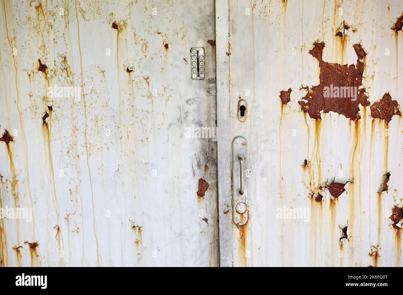 The old door to the building. Painted metal door with rust spots and