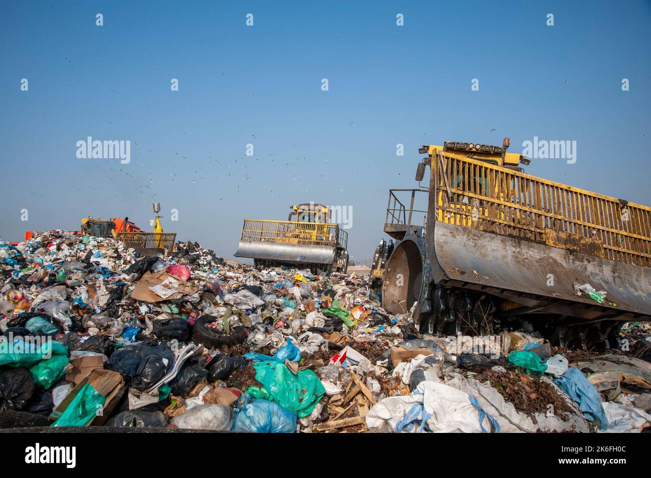 Municipal waste landfill. Workers with trucks and bulldozers at work in waste storage landfill
