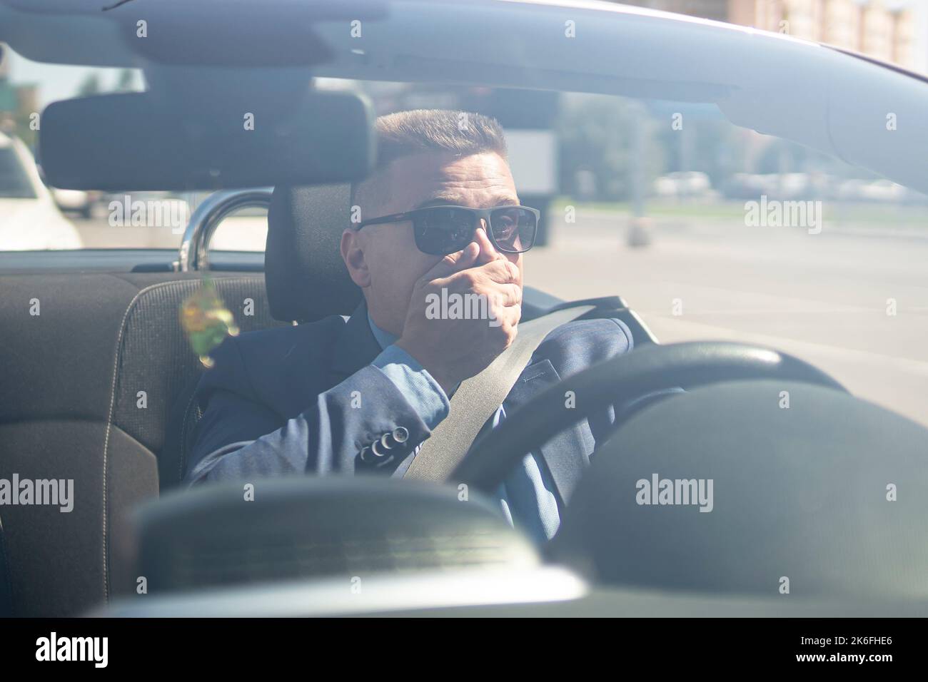shocked driver in the car. A businessman driving a car covers his mouth
