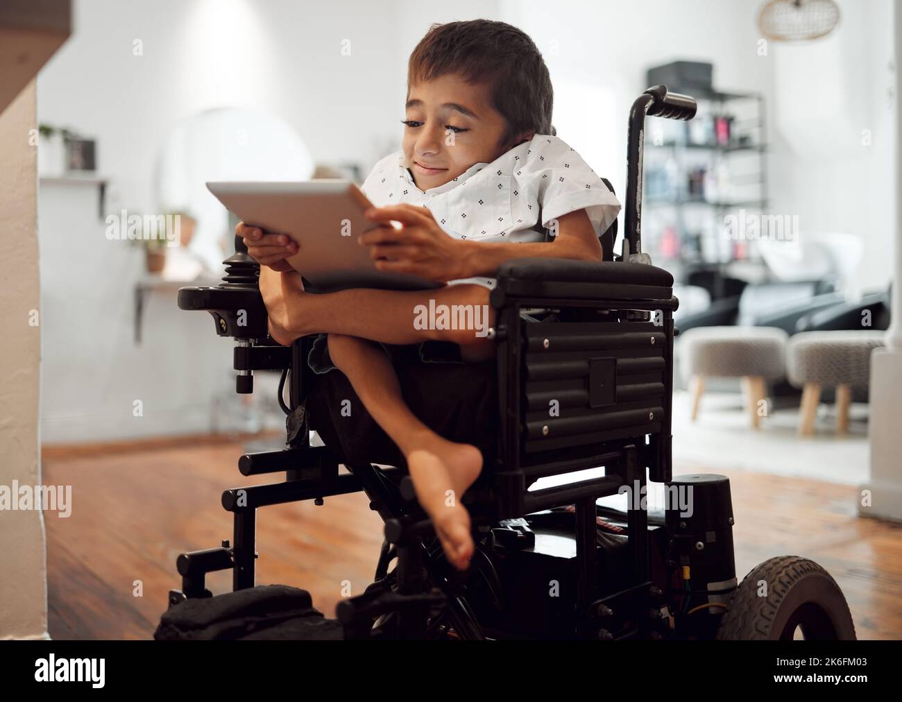 Wheelchair, disability and child with tablet for learning, video or games in home. Cerebral palsy, boy and disabled use tech on internet, app or web Stock Photo