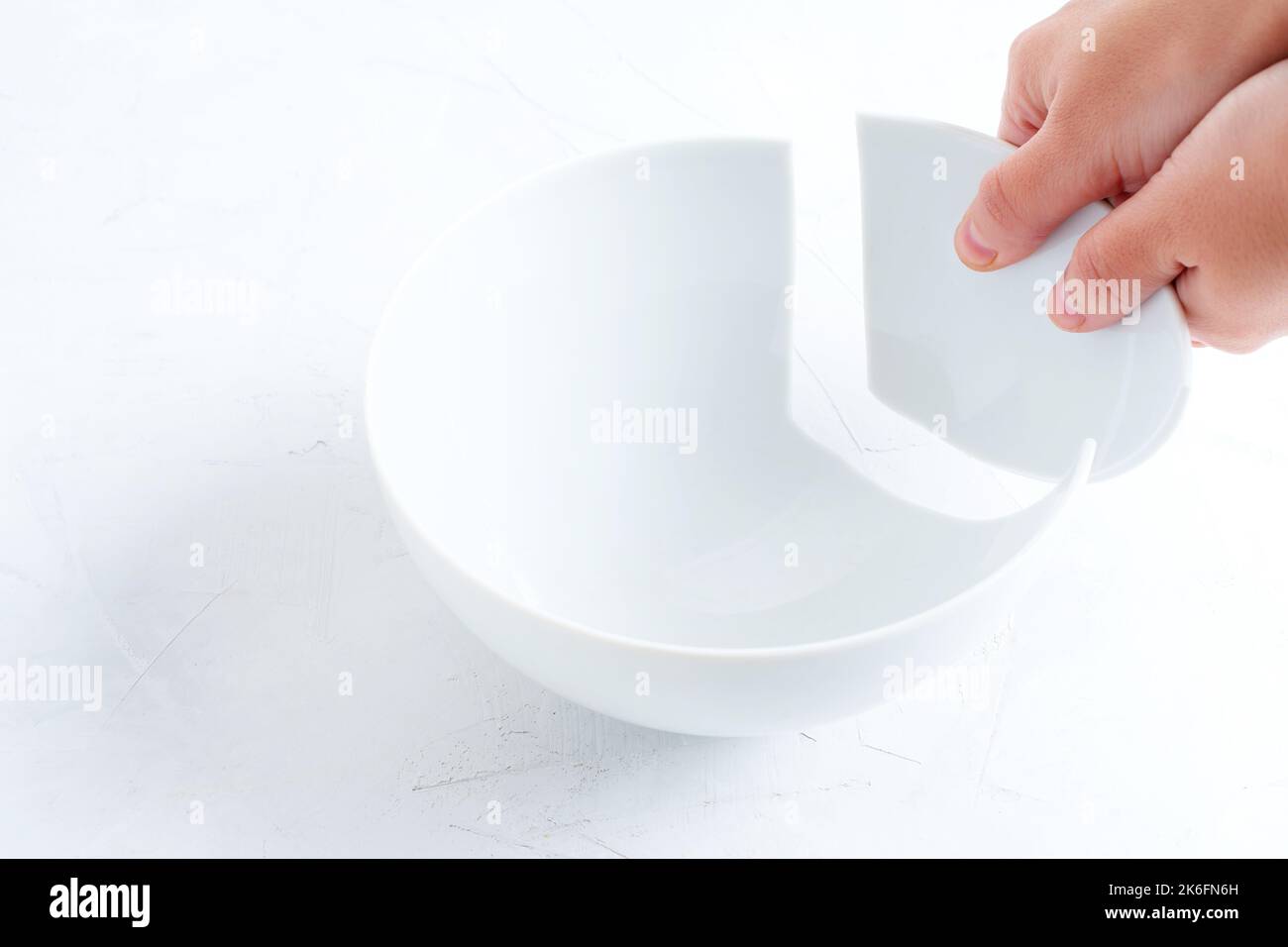 Broken white bowl piece in hands. Fixing a shattered kitchenware Stock