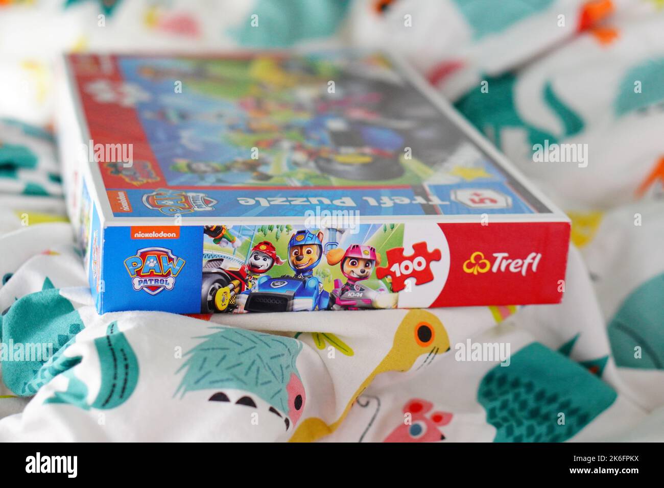 A closeup of Trefl brand Paw Patrol puzzle with 100 pieces on a bed ...