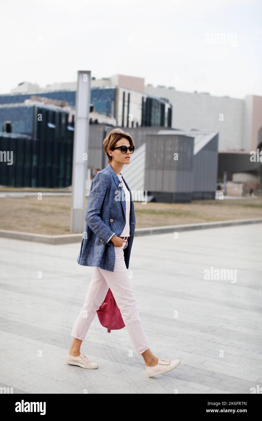 Beautiful emancipated business woman short hair confidently walking street. Determination fashionable woman wears jacket and pants Stock Photo