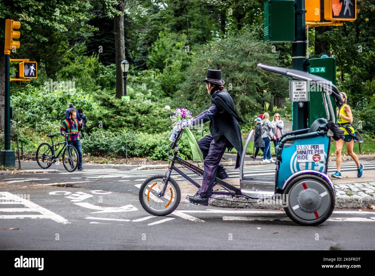 Central Park, New York City, USA, 13 October 2018. A rickshaw rider in suit and top hat riding through central park in autumn Stock Photo