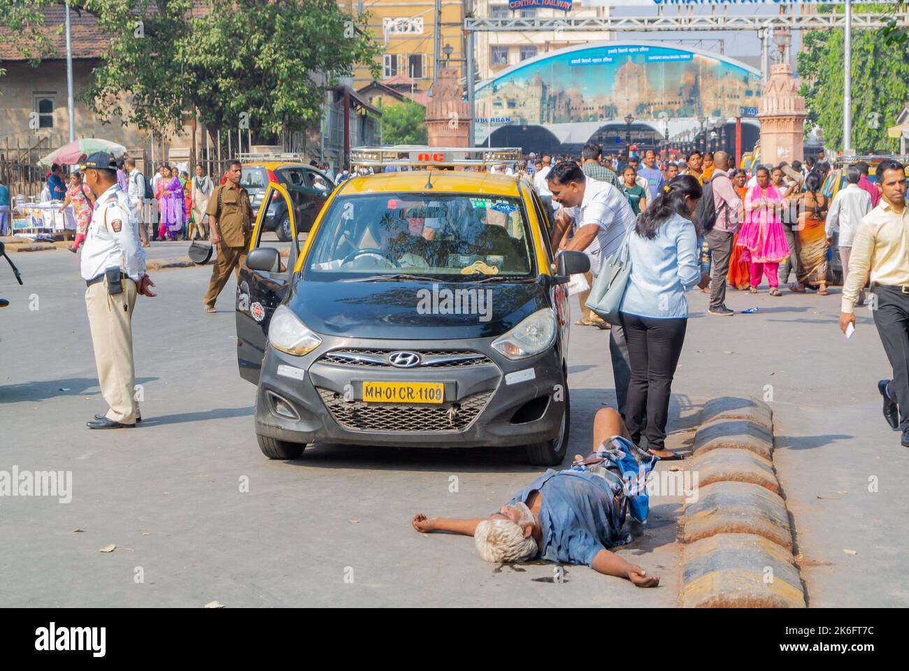 Mumbai, Maharashtra, South India, 31th of December 2019: A taxi and a drunk man laying in the street. Stock Photo