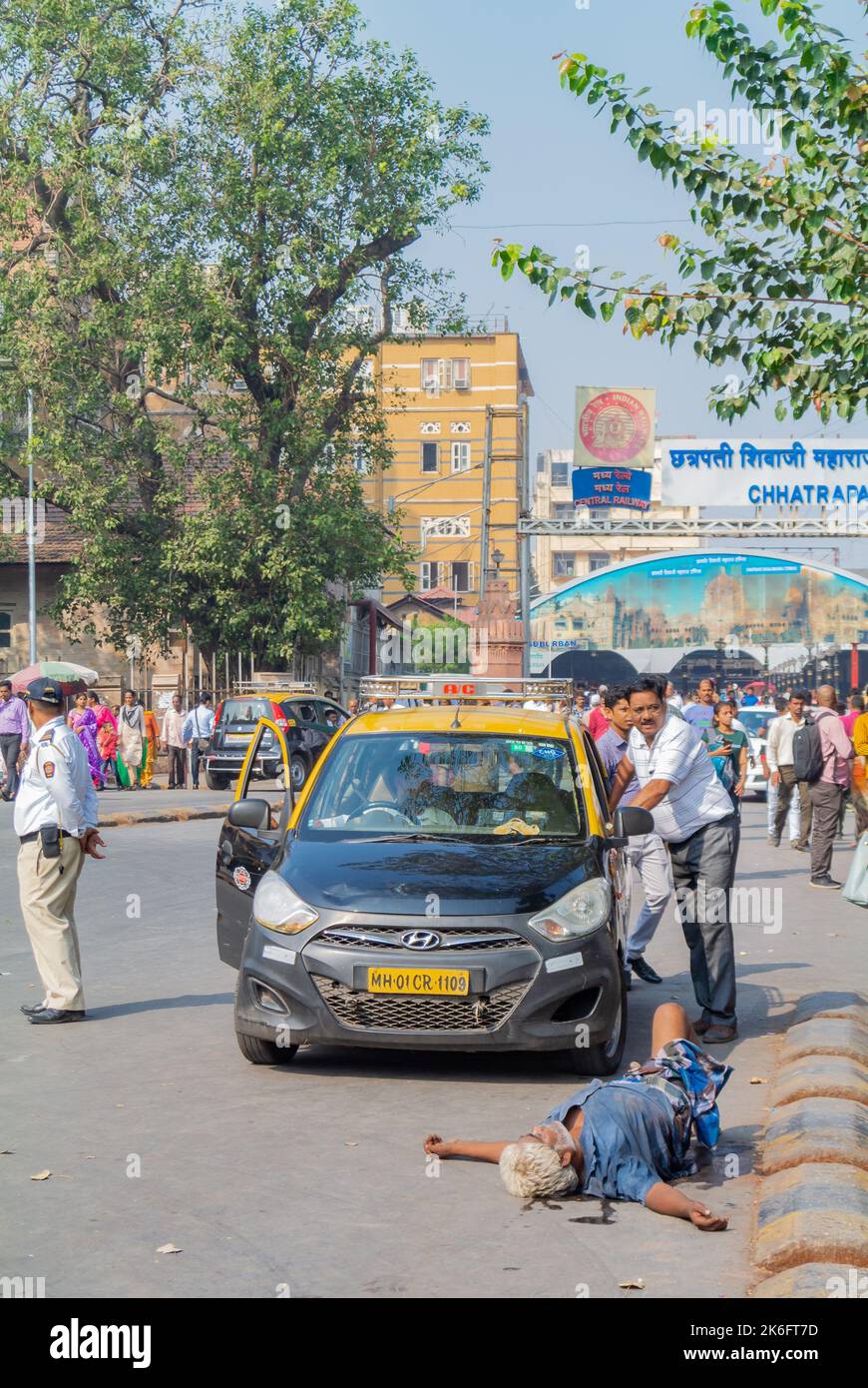 Mumbai, Maharashtra, South India, 31th of December 2019: A taxi and a drunk man laying in the street. Stock Photo