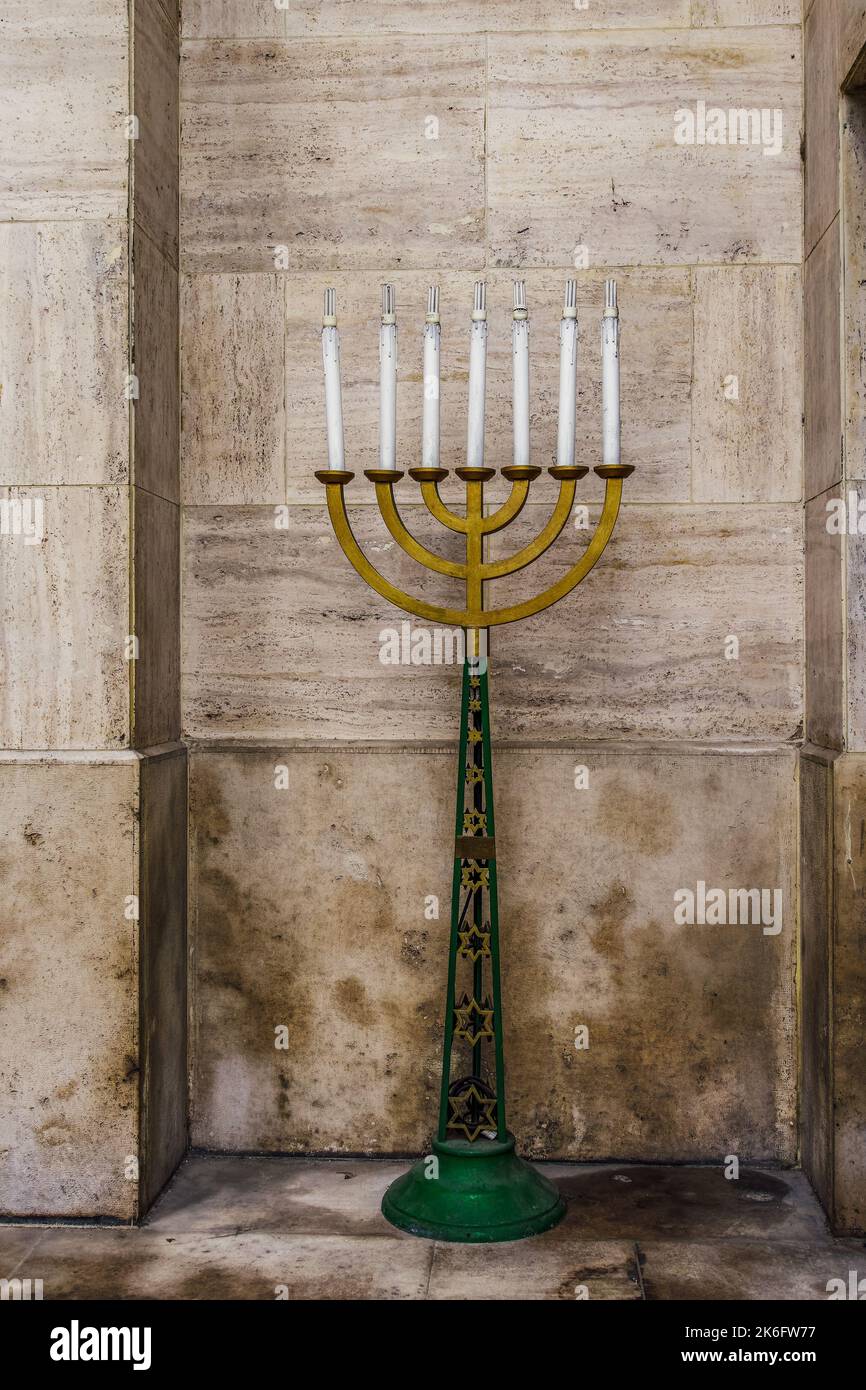 Large menorah lampstand, Judaism religious symbol with star of David decoration, standing against marble walls background. Stock Photo