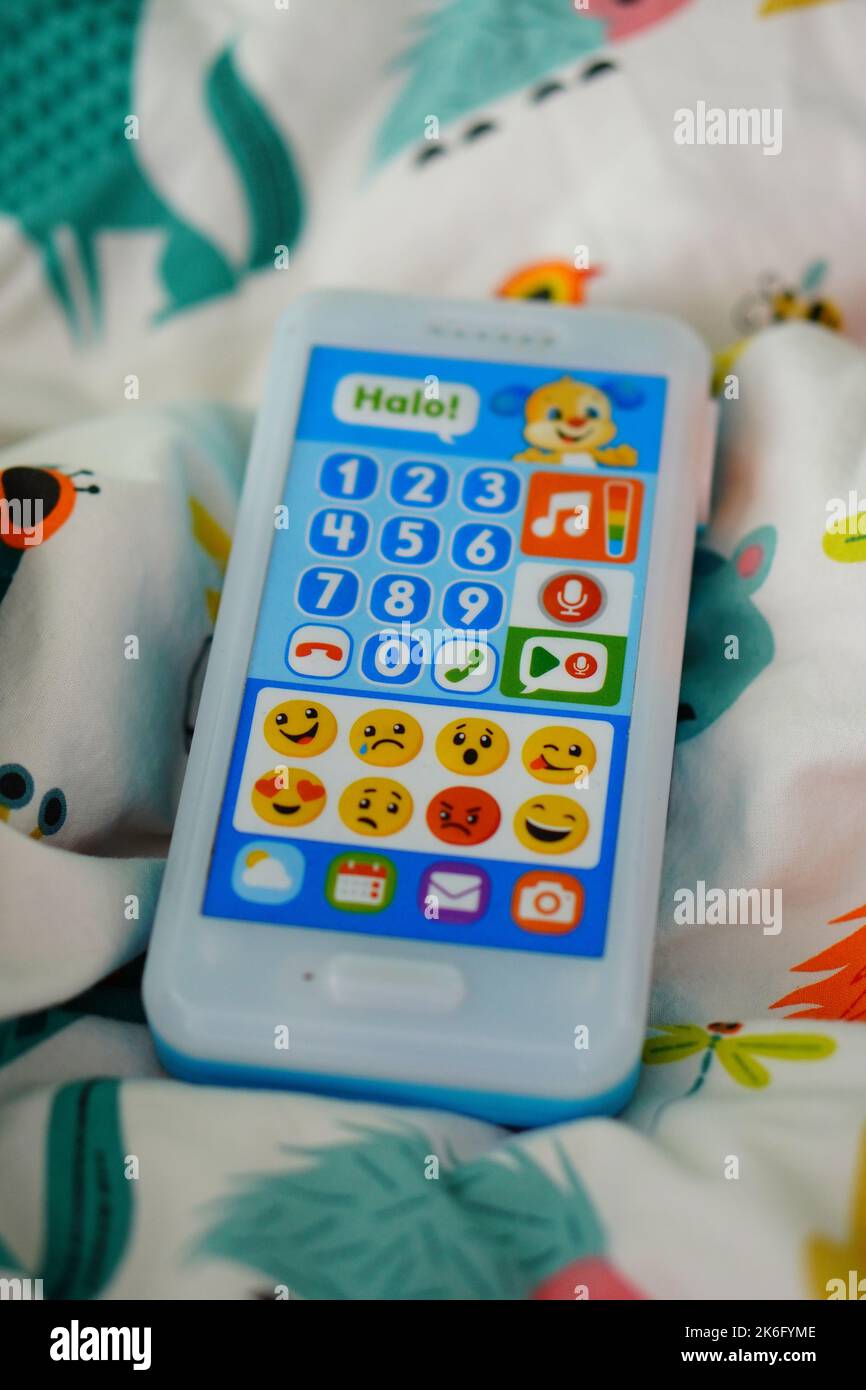 A vertical closeup of a Fisher Price brand toy phone with buttons on a bed sheet Stock Photo