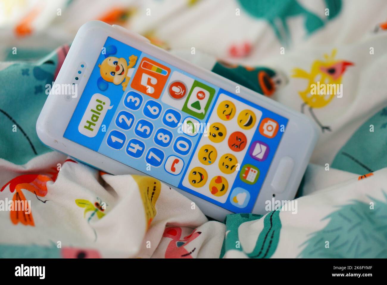 A closeup of a Fisher Price brand toy phone with buttons on a bed sheet Stock Photo