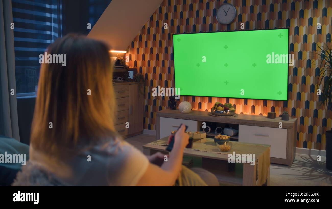 Woman switching channels with remote control. Couple sitting on sofa in