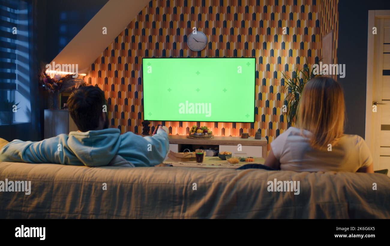 Woman switching channels with remote control. Couple sitting on couch