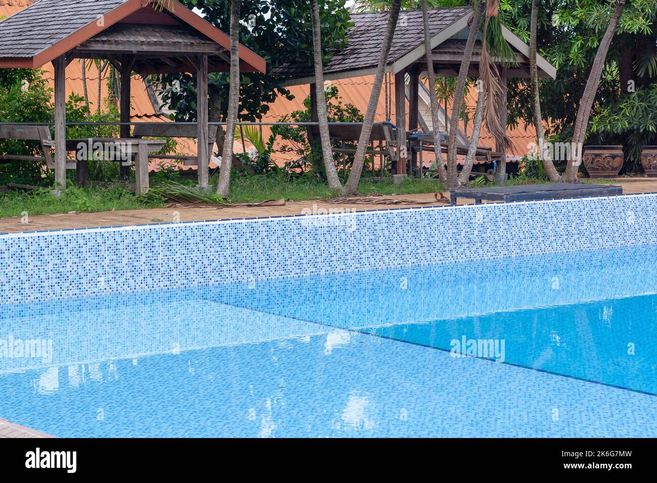 Pool is half filled with water and covered verandas with tables and ...