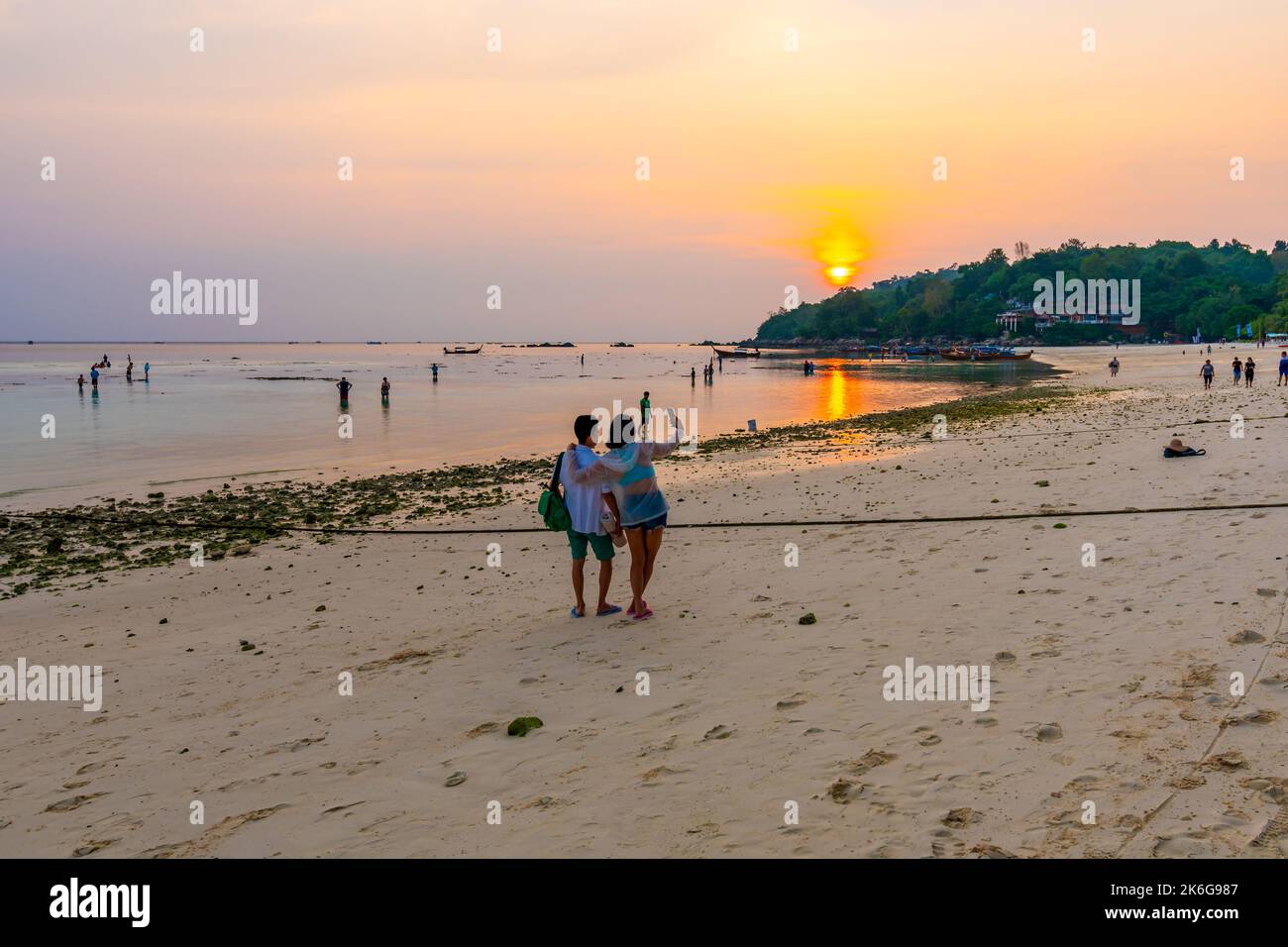 Koh Lipe, Thailand - 13.11.2019: Tourists are taking selfie photos during sunset at Ko Lipe island, Thailand. Beautiful and romantic time for photogra Stock Photo