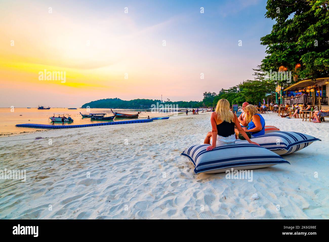 Koh Lipe, Thailand - 13.11.2019: Tourist are sitting on big pillows at Ko Lipe restaurant. Beach relaxation on pillows with summer drinks. Sunset in b Stock Photo