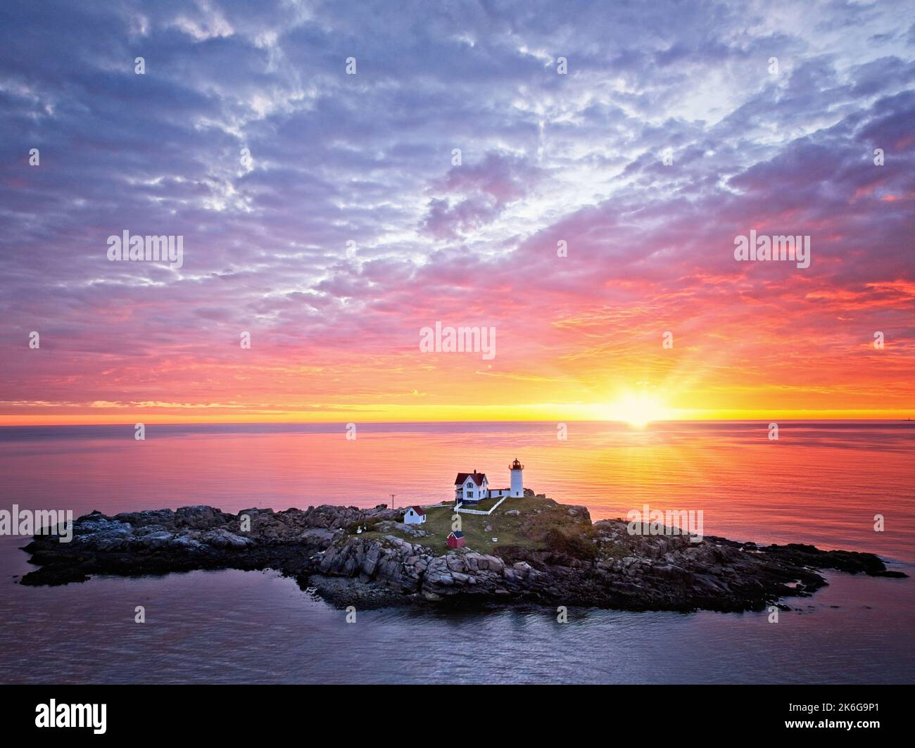 Nubble Lighthouse Aerial Sunrise - Aerial view of a beautiful dramatic sky with the rising sun behind the iconic quintessential Nubble Light at Cape N Stock Photo