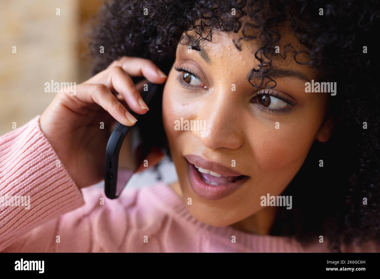 Happy african american woman sitting on sofa in living room, talking on ...