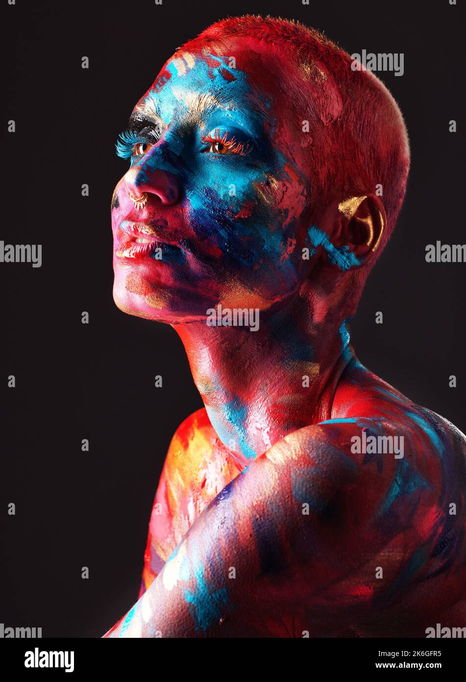Reality gets boring. an attractive young woman posing alone in the studio with paint on her face and body. Stock Photo