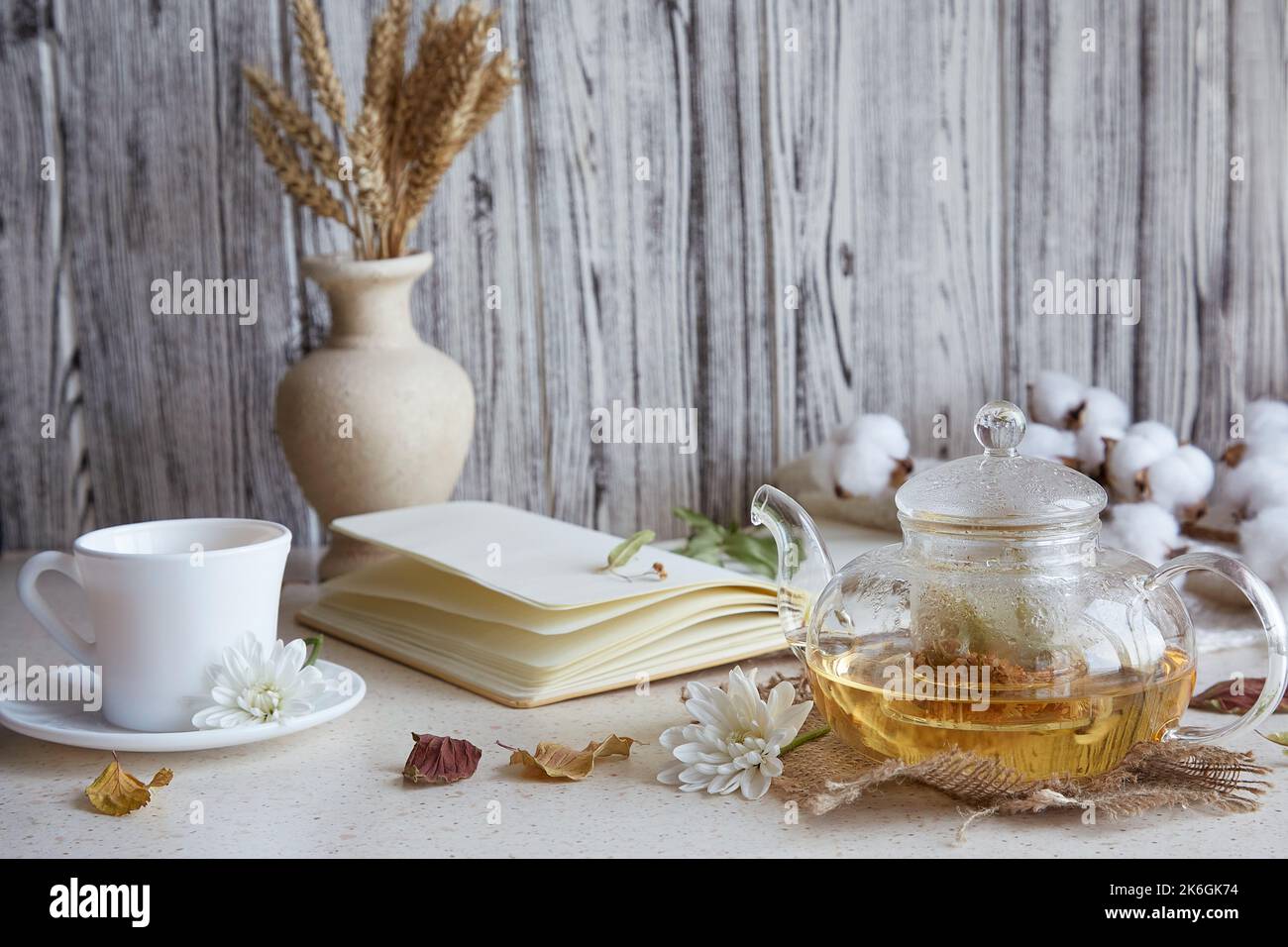 Aesthetic herbal linden tea in teapot with cup of tea. Wheat, leaves