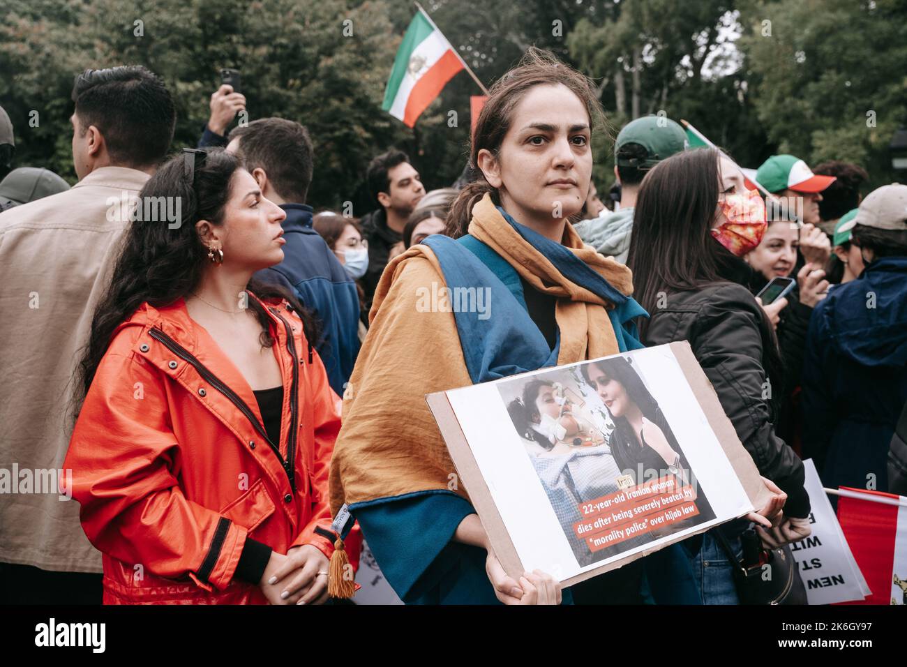 New York, United States. 01st Oct, 2022. A woman holds a protest sign dispalying two photos of Mahsa Ahmini side by side. In one photo, Mahsa Ahmini is smiling. In the other, she is intubated after being beaten by Iran's so-called morality police. An Iranian flag is seen in the background. Woman, Life, Freedom protest against Iran's hardline Islamic regime held in New York. Protests broke out after Mahsa Amini's death in the custody of Iran's so-called moral police. Credit: SOPA Images Limited/Alamy Live News Stock Photo