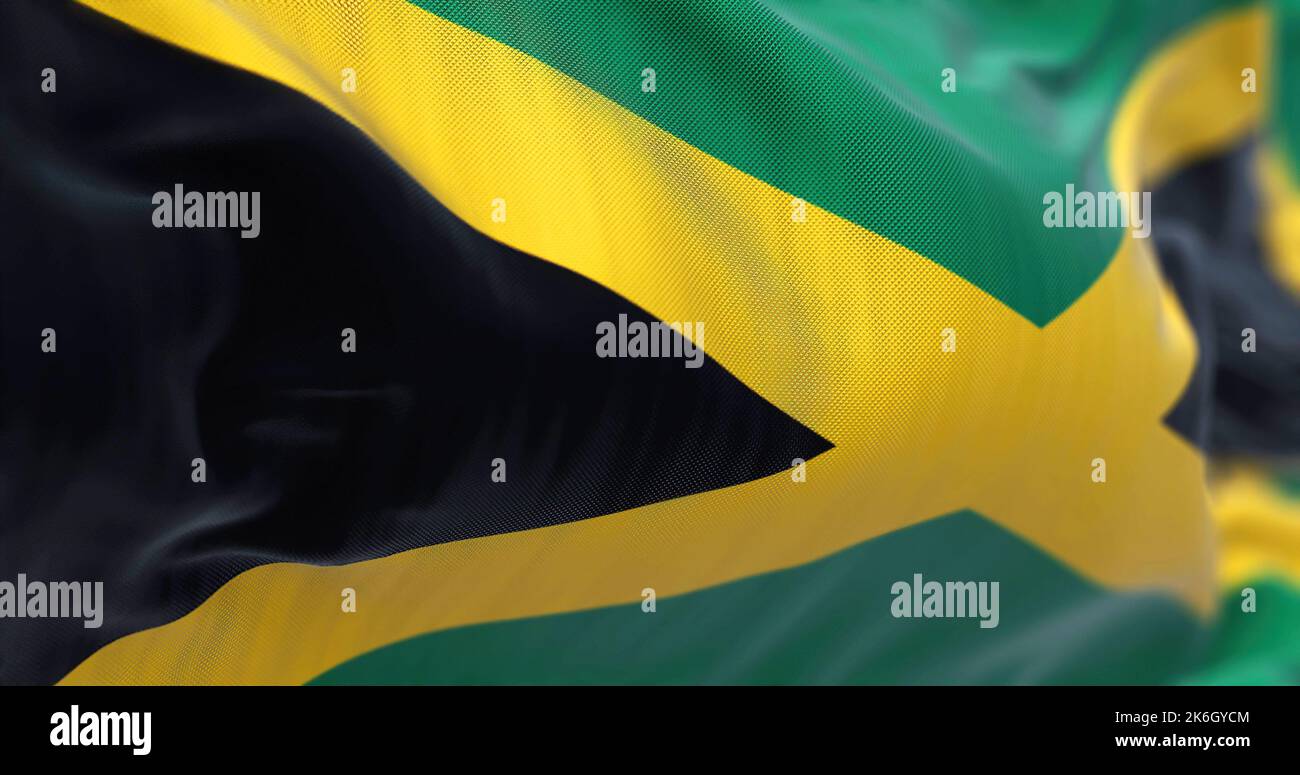 Close-up view of the Jamaica national flag waving in the wind. Jamaica is an island country situated in the Caribbean Sea. Fabric textured background. Stock Photo