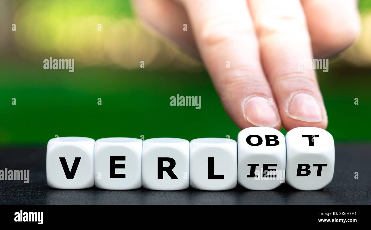 Hand turns dice and changes the German word 'verliebt' (in love) to